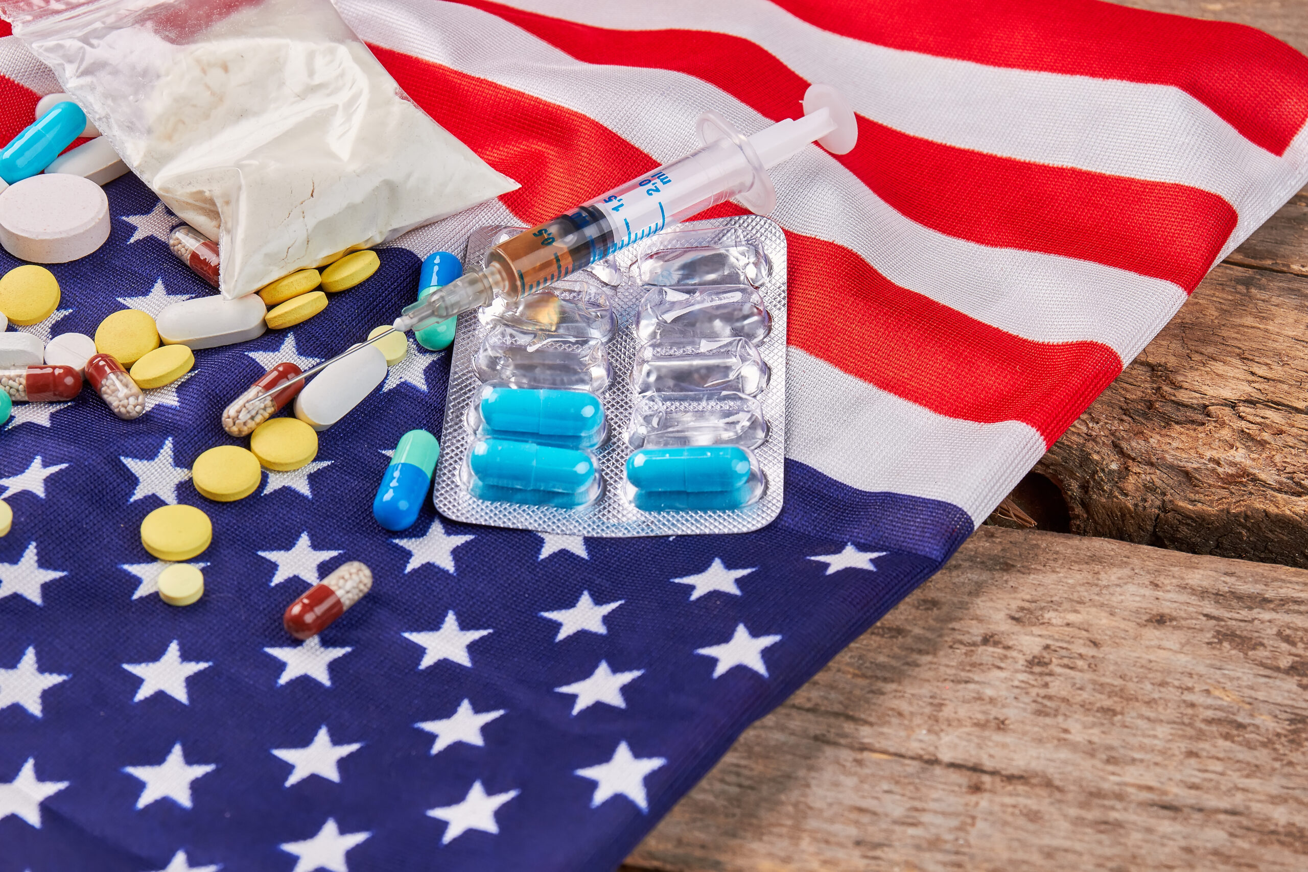 American flag, narcotics close up. Flag of America, syringe, pills, packet, wooden floor.