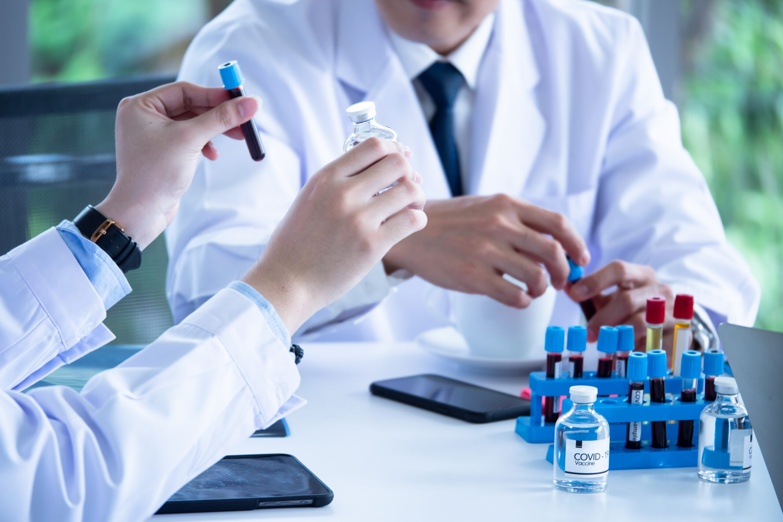 Scientist discussing with colleague about covid 19 vaccine in meeting room at hospital
